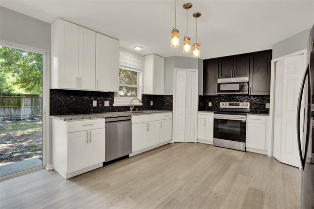 809 Deer Glen Ct, Fruitland Park, FL 34731 - kitchen featuring appliances with stainless steel finishes, light wood finished floors, decorative backsplash, and white cabinets