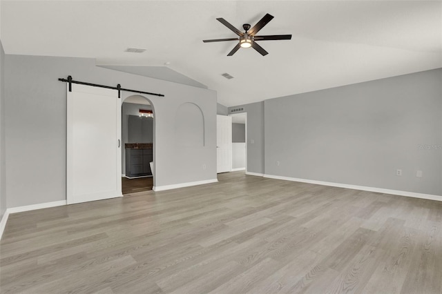 809 Deer Glen Ct, Fruitland Park, FL 34731 - empty room with a barn door, ceiling fan, lofted ceiling, wood finished floors, and baseboards