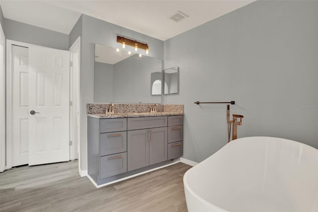 809 Deer Glen Ct, Fruitland Park, FL 34731 - full bath featuring double vanity, a freestanding bath, wood finished floors, and baseboards