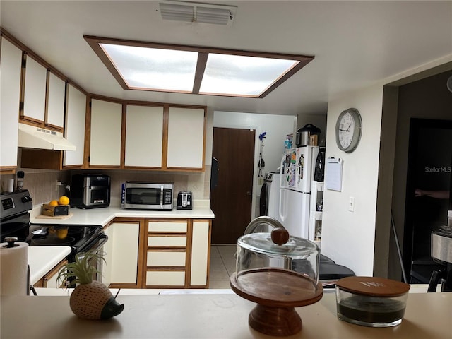 707 Carpenters Way Unit 50, Lakeland, FL 33809 - kitchen featuring stainless steel appliances, under cabinet range hood, independent washer and dryer, light countertops, and light tile patterned flooring