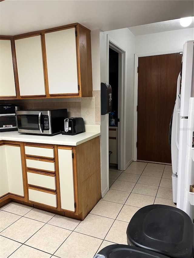 707 Carpenters Way Unit 50, Lakeland, FL 33809 - kitchen featuring light countertops, light tile patterned floors, stainless steel microwave, and backsplash