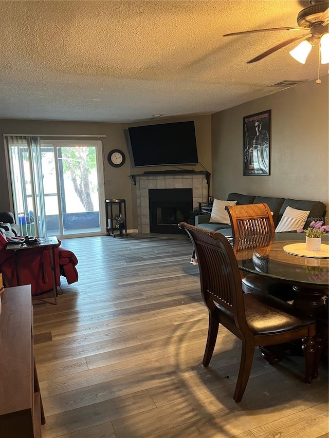 707 Carpenters Way Unit 50, Lakeland, FL 33809 - dining room with a textured ceiling, a fireplace, a ceiling fan, and wood finished floors