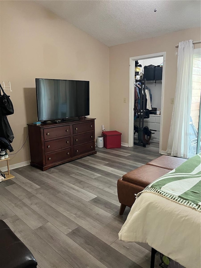707 Carpenters Way Unit 50, Lakeland, FL 33809 - bedroom featuring light wood finished floors, a walk in closet, a textured ceiling, baseboards, and lofted ceiling