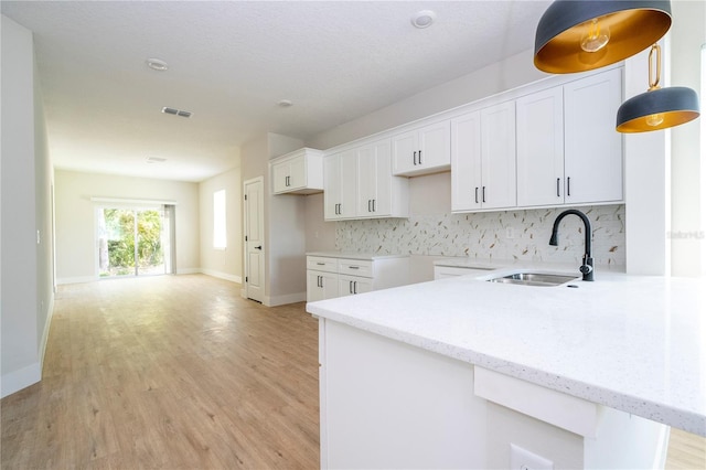 33 W 7th St, Apopka, FL 32703 - kitchen with a sink, decorative backsplash, light wood-style flooring, and white cabinets