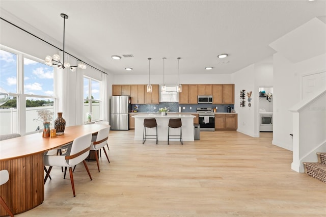 701 Dennis Ave, Orlando, FL 32807 - kitchen with stainless steel appliances, light countertops, a kitchen island, decorative backsplash, and washer / dryer