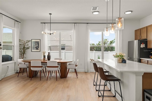 701 Dennis Ave, Orlando, FL 32807 - kitchen with freestanding refrigerator, a kitchen breakfast bar, light wood-type flooring, brown cabinetry, and light countertops