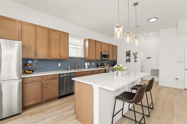 701 Dennis Ave, Orlando, FL 32807 - kitchen featuring appliances with stainless steel finishes, light wood-style floors, a kitchen bar, and brown cabinetry