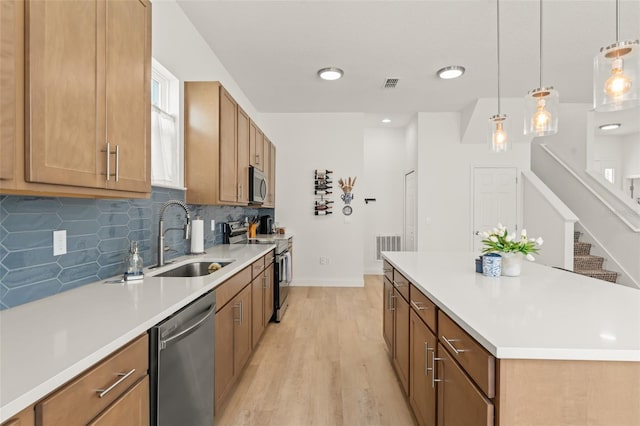 701 Dennis Ave, Orlando, FL 32807 - kitchen featuring appliances with stainless steel finishes, a sink, light wood-style floors, brown cabinetry, and decorative backsplash