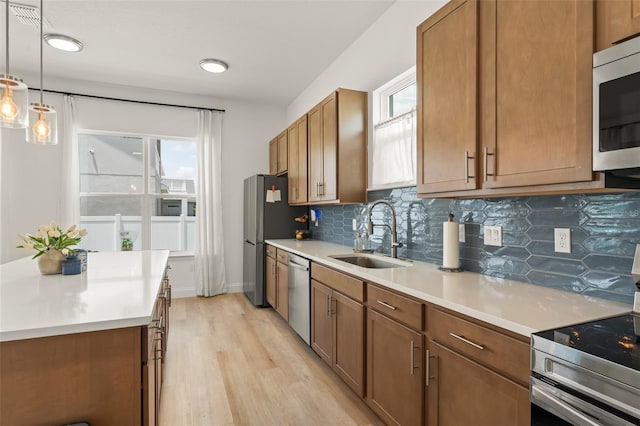 701 Dennis Ave, Orlando, FL 32807 - kitchen featuring appliances with stainless steel finishes, a sink, brown cabinetry, light wood-style flooring, and light countertops