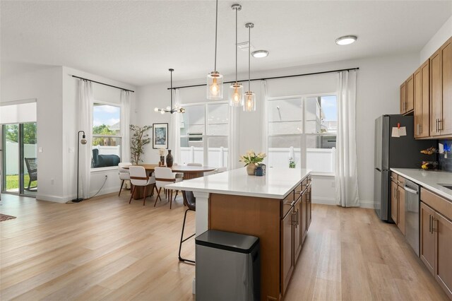 701 Dennis Ave, Orlando, FL 32807 - kitchen with appliances with stainless steel finishes, light wood-style floors, a center island, light countertops, and brown cabinetry