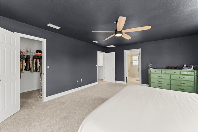 701 Dennis Ave, Orlando, FL 32807 - bedroom featuring light carpet, a walk in closet, baseboards, ceiling fan, and a textured ceiling