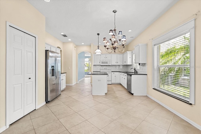 9644 Myrtle Creek Ln, Orlando, FL 32832 - kitchen featuring appliances with stainless steel finishes, arched walkways, a chandelier, a center island, and dark countertops
