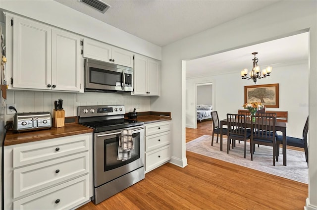 1202 Marshall Ct, Eustis, FL 32726 - kitchen featuring stainless steel appliances, butcher block counters, a chandelier, light wood-style floors, and decorative backsplash