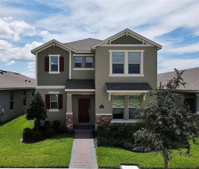 16391 Admirals Cove Ln, Winter Garden, FL 34787 - craftsman-style home with stucco siding, roof with shingles, a front yard, and stone siding