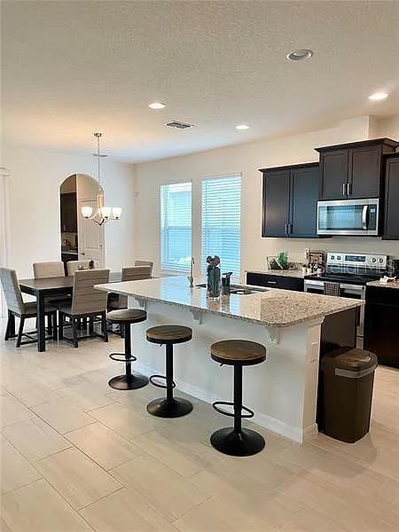 16391 Admirals Cove Ln, Winter Garden, FL 34787 - kitchen featuring stainless steel appliances, a kitchen breakfast bar, an island with sink, light stone countertops, and recessed lighting