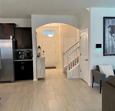 16391 Admirals Cove Ln, Winter Garden, FL 34787 - kitchen with freestanding refrigerator, arched walkways, and dark brown cabinetry