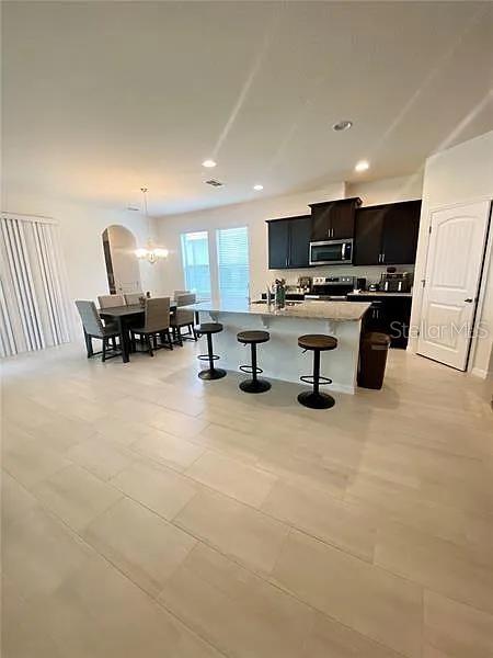 16391 Admirals Cove Ln, Winter Garden, FL 34787 - kitchen with stainless steel appliances, a kitchen bar, an island with sink, pendant lighting, and light countertops