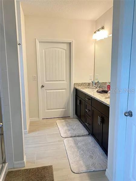 16391 Admirals Cove Ln, Winter Garden, FL 34787 - full bath featuring double vanity, a shower stall, and baseboards