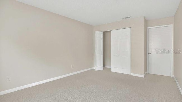 648 Kenwick Cir Unit 102, Casselberry, FL 32707 - unfurnished bedroom with light carpet, baseboards, and a closet