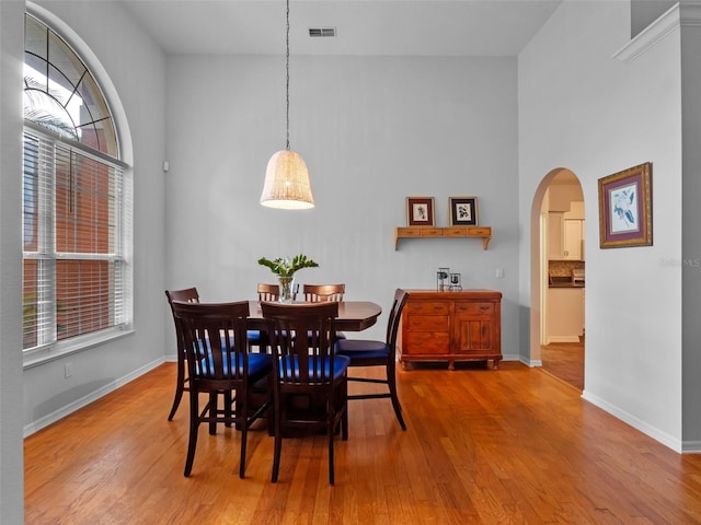 3518 Edlingham Ct, Belle Isle, FL 32812 - dining room featuring wood finished floors, arched walkways, baseboards, and a towering ceiling