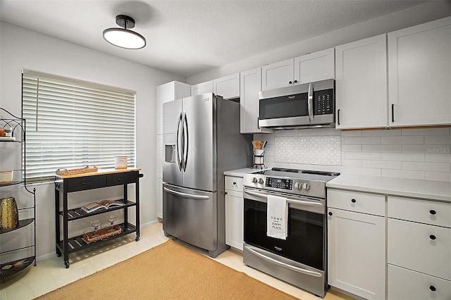 184 Sandlewood Trl Unit 2, Winter Park, FL 32789 - kitchen with appliances with stainless steel finishes, decorative backsplash, light countertops, and white cabinets