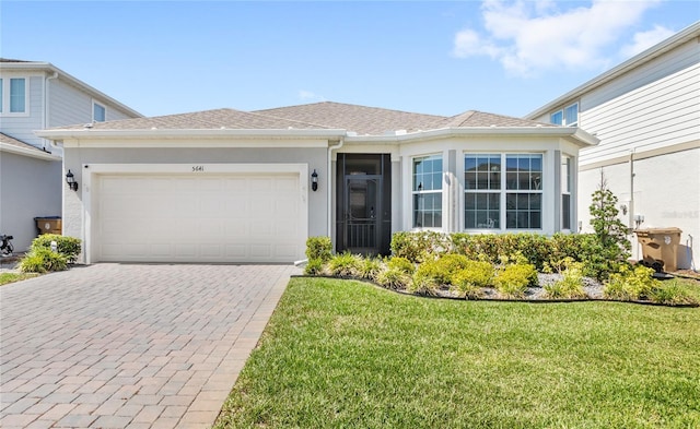 5641 Oak Knoll Dr, Saint Cloud, FL 34771 - view of front of property with decorative driveway, stucco siding, an attached garage, and a front yard