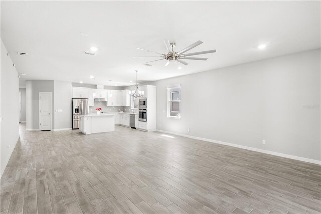 5641 Oak Knoll Dr, Saint Cloud, FL 34771 - unfurnished living room featuring a ceiling fan, a chandelier, light wood-type flooring, baseboards, and recessed lighting
