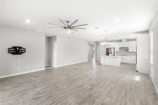 5641 Oak Knoll Dr, Saint Cloud, FL 34771 - unfurnished living room featuring ceiling fan, a chandelier, light wood-style flooring, baseboards, and recessed lighting