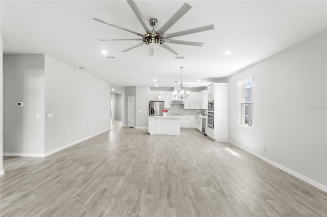 5641 Oak Knoll Dr, Saint Cloud, FL 34771 - unfurnished living room with ceiling fan, light wood finished floors, recessed lighting, baseboards, and a chandelier
