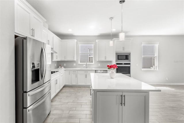 5641 Oak Knoll Dr, Saint Cloud, FL 34771 - kitchen featuring stainless steel appliances, light wood-type flooring, tasteful backsplash, a center island, and white cabinetry