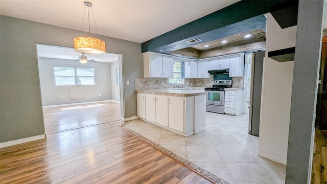 2928 NE 14th Ave, Ocala, FL 34479 - kitchen featuring appliances with stainless steel finishes, under cabinet range hood, a peninsula, light countertops, and white cabinetry
