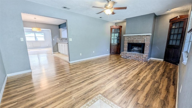 2928 NE 14th Ave, Ocala, FL 34479 - unfurnished living room with light wood-style flooring, baseboards, ceiling fan, and a textured ceiling