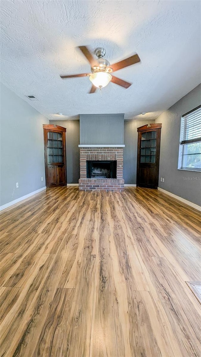 2928 NE 14th Ave, Ocala, FL 34479 - unfurnished living room with wood finished floors, a textured ceiling, ceiling fan, a fireplace, and baseboards