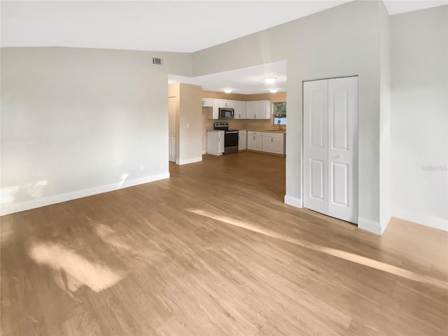 1736 Taylor Lake Pl, Largo, FL 33778 - unfurnished living room with baseboards, light wood-style floors, and a sink