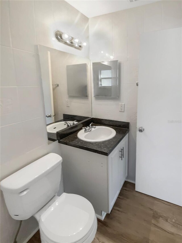 1736 Taylor Lake Pl, Largo, FL 33778 - half bathroom featuring tile walls, toilet, vanity, wood finished floors, and decorative backsplash