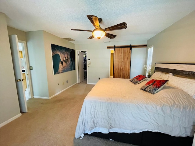 3565 E Lake Dr, Land O Lakes, FL 34639 - carpeted bedroom with baseboards, a barn door, a ceiling fan, a textured ceiling, and a walk in closet