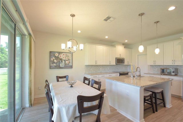 5908 Paxton Ct, Apopka, FL 32703 - kitchen with appliances with stainless steel finishes, a sink, decorative backsplash, white cabinetry, and light wood-style flooring