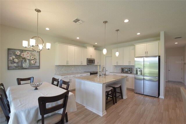 5908 Paxton Ct, Apopka, FL 32703 - kitchen with stainless steel appliances, decorative backsplash, white cabinets, light wood finished floors, and recessed lighting