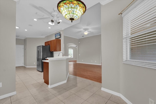 3304 Bennington Ct, Winter Park, FL 32792 - kitchen featuring a ceiling fan, arched walkways, freestanding refrigerator, light tile patterned floors, and brown cabinetry