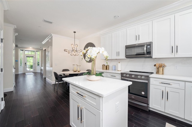 152 Riggings Way, Clermont, FL 34711 - kitchen with appliances with stainless steel finishes, dark wood-style floors, a chandelier, white cabinetry, and a center island