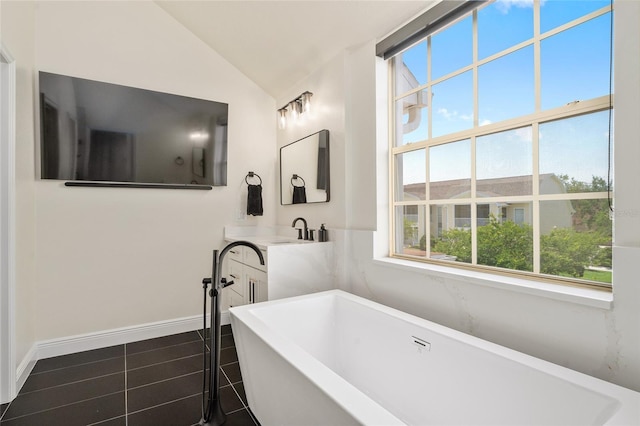 152 Riggings Way, Clermont, FL 34711 - bathroom with a soaking tub, lofted ceiling, vanity, tile patterned flooring, and baseboards