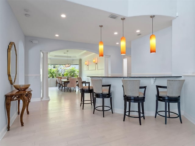 4071 Isabella Cir, Windermere, FL 34786 - kitchen featuring decorative columns, light wood-style flooring, recessed lighting, a breakfast bar area, and baseboards