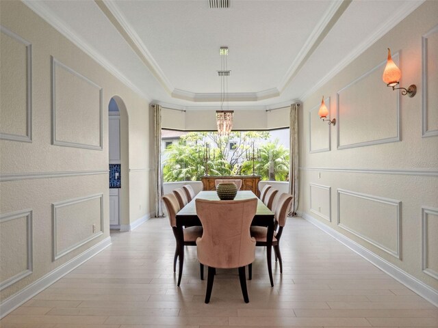 4071 Isabella Cir, Windermere, FL 34786 - dining area featuring a raised ceiling, light wood finished floors, a chandelier, arched walkways, and crown molding