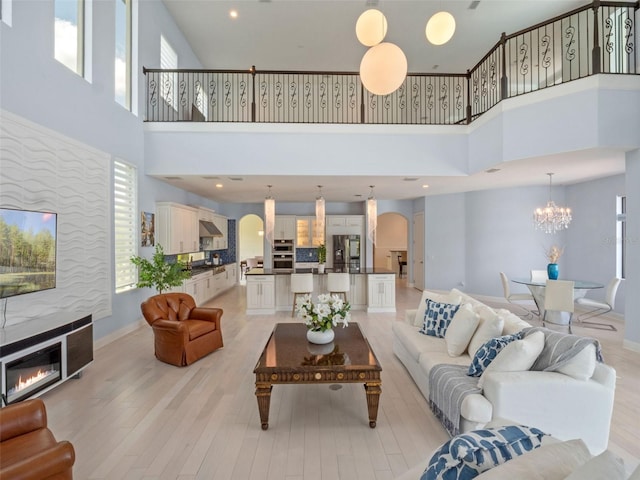 4071 Isabella Cir, Windermere, FL 34786 - living area featuring arched walkways, a glass covered fireplace, a towering ceiling, light wood-style flooring, and a chandelier