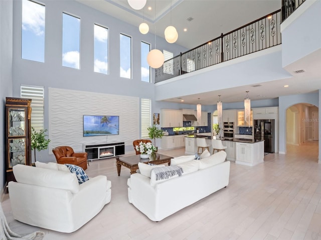4071 Isabella Cir, Windermere, FL 34786 - living area with a towering ceiling, arched walkways, a glass covered fireplace, and light wood-style floors