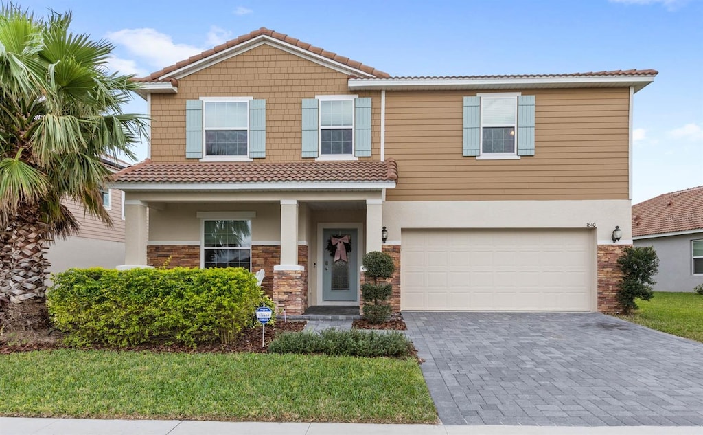 1640 Oak Blossom Dr, Davenport, FL 33837 - view of front of property with a tile roof, decorative driveway, stucco siding, and a garage