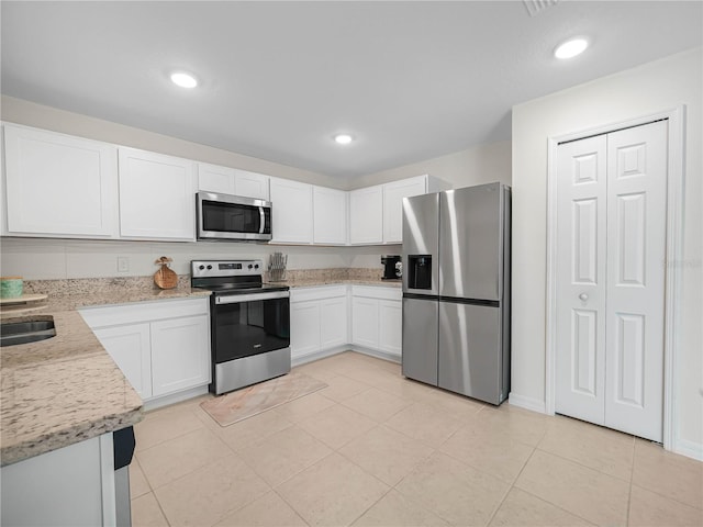 440 Patricia Alford Dr, Haines City, FL 33844 - kitchen with appliances with stainless steel finishes, white cabinetry, light tile patterned floors, recessed lighting, and light stone counters