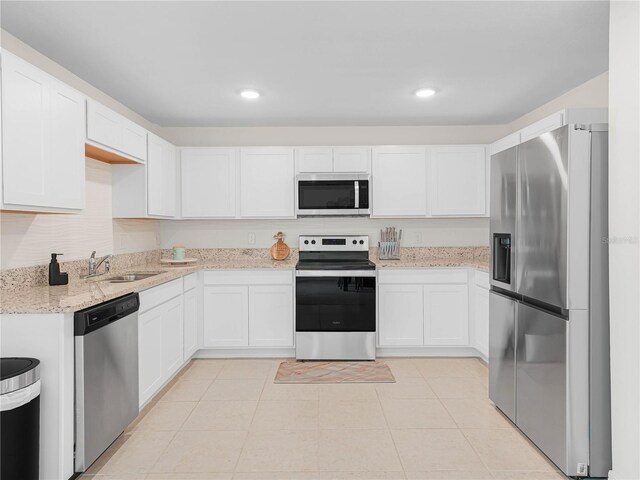 440 Patricia Alford Dr, Haines City, FL 33844 - kitchen with stainless steel appliances, a sink, white cabinets, light stone counters, and recessed lighting