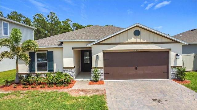 2836 Sanctuary Dr, Clermont, FL 34714 - view of front of home featuring roof with shingles, stone siding, an attached garage, decorative driveway, and stucco siding