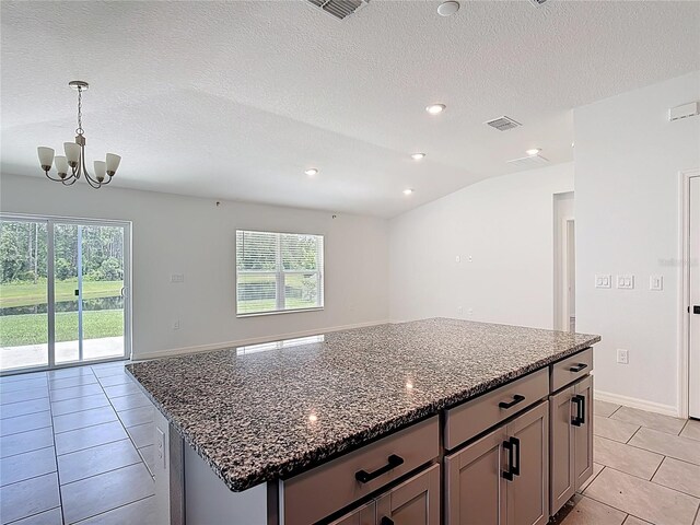 2836 Sanctuary Dr, Clermont, FL 34714 - kitchen featuring light tile patterned floors, plenty of natural light, a chandelier, a kitchen island, and a textured ceiling